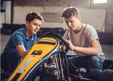 Dwóch młodych uczestników Racing Future Academy pracujących nad budową gokarta - praktyczna nauka STEAM